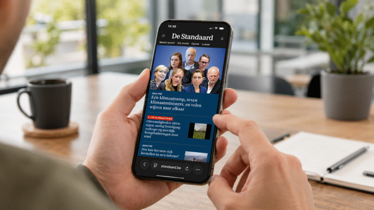 Persoon heeft smartphone in de hand en scrolt op de nieuwssite van Het Belang van Limburg, een van de Mediahuis-nieuwstitels
